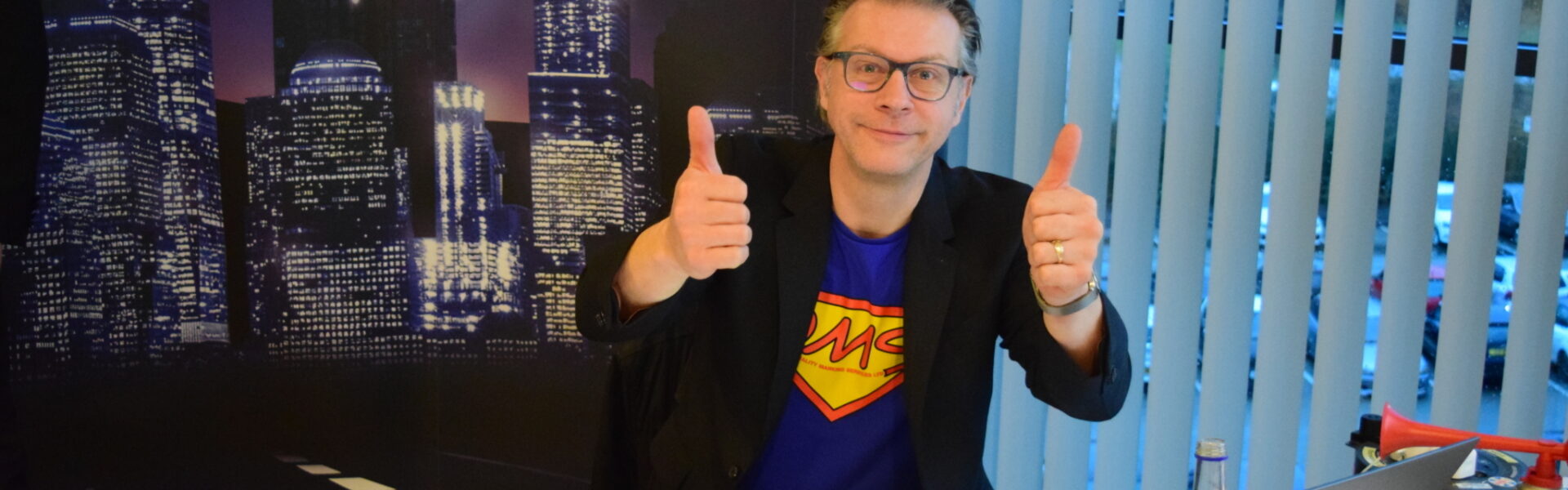 Greg Approval double thumbs up sat at desk