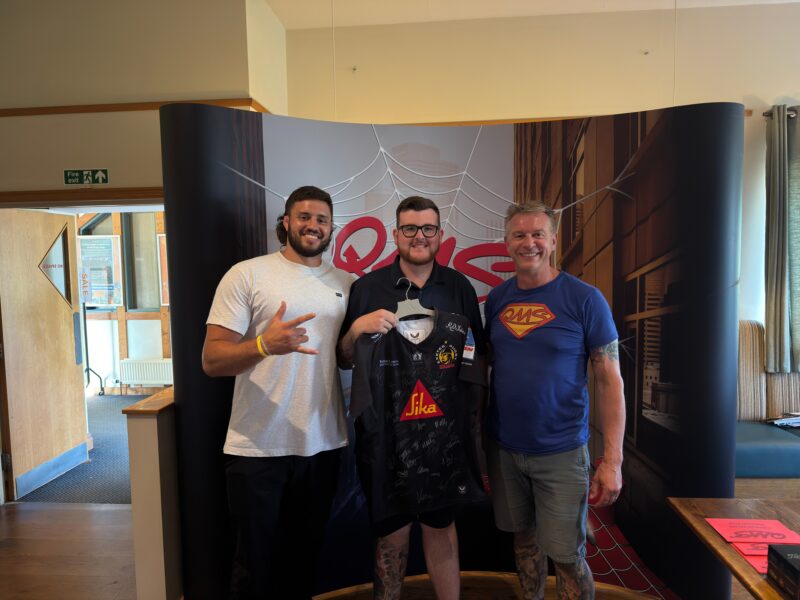 Ethan Roots Exeter Chiefs with Signed Shirt winner from Carysil and Greg Clark stood by the QMS Banner
