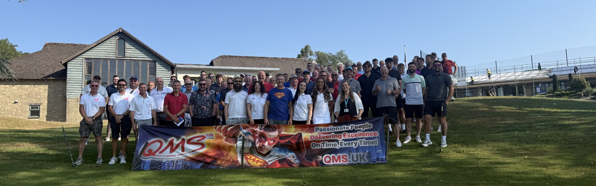Fairway to Devon 2026 Golf Day participants and organisers at Dainton Golf Club in front of QMS banner