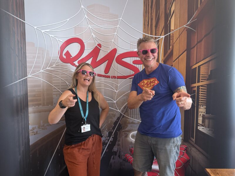 Georgia from Hospicare with Greg Clark from QMS stood by the QMS Banner