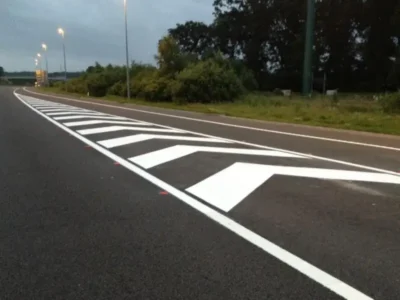 Freshly applied MMA hatched chevron markings and white edge lines at a slip road merge