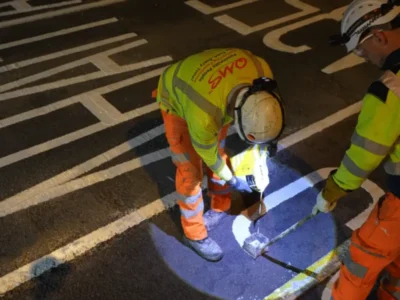 Operatives hand applying MMA road marking to a junction box during a night road closure