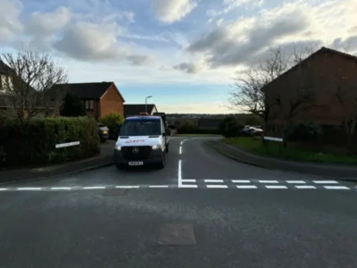 Newly applied MMA give way markings at a residential road junction with a works van parked alongside