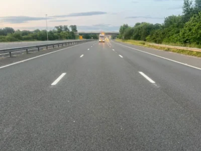 Newly applied MMA lane markings and edge lines on a motorway carriageway with a works vehicle ahead
